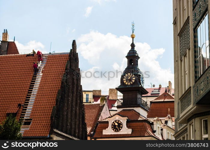 Scenic view of the historical center of Prague: houses, buildings, palaces, landmarks of old town with the characteristic and picturesque red rooftops and multi-coloured walls. Carpenters working on rooftop