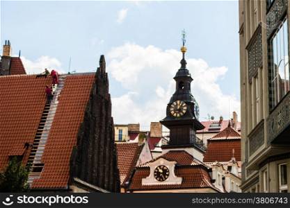 Scenic view of the historical center of Prague: houses, buildings, palaces, landmarks of old town with the characteristic and picturesque red rooftops and multi-coloured walls. Carpenters working on rooftop