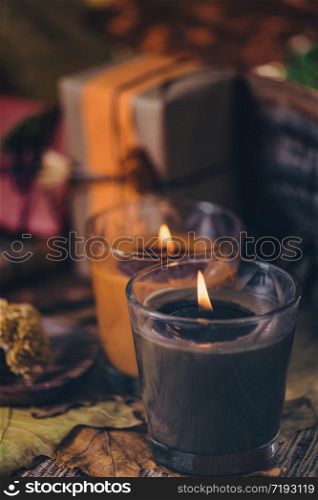 Scented brown and orange candles with presents, dried flowers and leaf decoration on table. Copy space. Scented Candles, Presents, Dried Flowers and Leaf Decoration on a Table