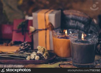 Scented brown and orange candles with presents, dried flowers and leaf decoration on table. Copy space. Scented Candles, Presents, Dried Flowers and Leaf Decoration on a Table