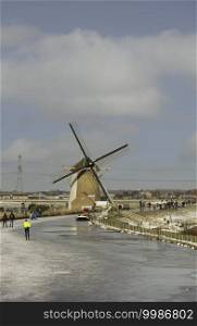 Schipluiden,Holland,14-feb-2021 people skating on the canal near the windmill, it has been years ago that is was so cold in Holland, people can skate. People skating om ice with windmill as background