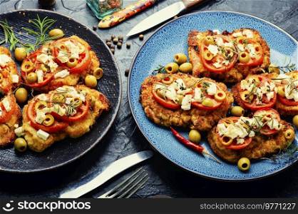 Schnitzel, breaded and fried thin layer of meat. Austrian dish. Schnitzel with olives and tomato