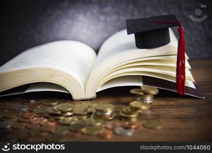 Scholarship for education concept with money coin on wooden with dark background and graduation cap on a open book