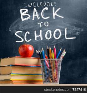 School accessories against blackboard. Back to School. Accessories, books and fresh apple against chalkboard