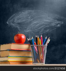 School accessories against blackboard. Back to School. Accessories, books and fresh apple against chalkboard