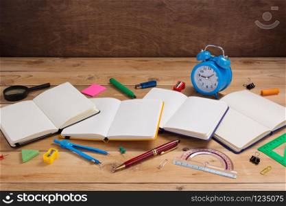 school accessories and supplies with paper notebook at wooden table background surface table
