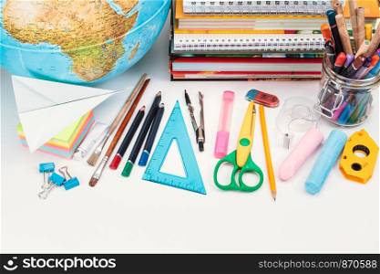 School accessories, pencil, pen, scissors, blank sheet of paper on a wooden desk. View from above