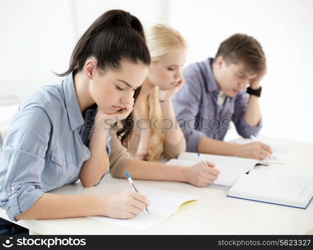 school and education concept - group of tired students with notebooks at school