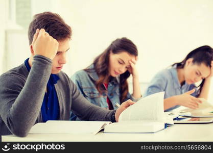 school and education concept - group of tired students with notebooks at school