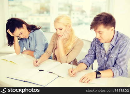 school and education concept - group of tired students with notebooks at school