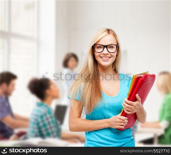 school and education concept - smiling student in eyeglasses with folders