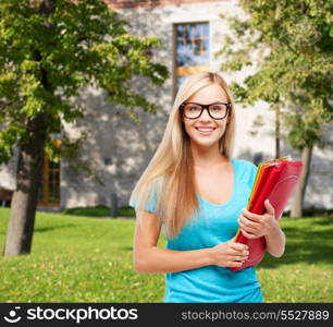 school and education concept - smiling student in eyeglasses with folders