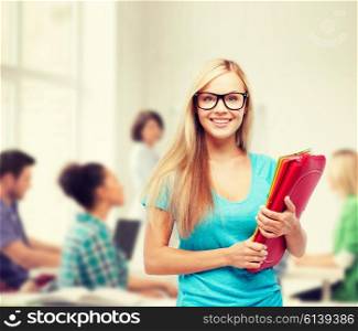 school and education concept - smiling student in eyeglasses with folders. smiling student with folders in eyeglasses
