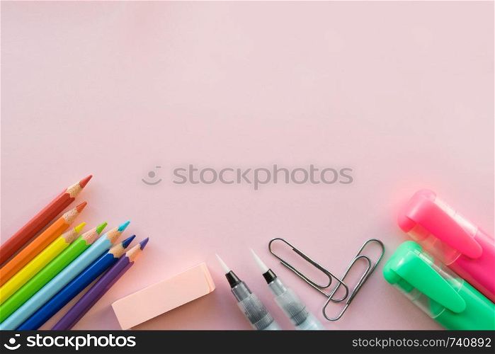 School and Office drawing supplies on pink background. Free space for text. Back to school. Top view border of colour pencils, marker and brushes. Office supplies on pink background. Free space