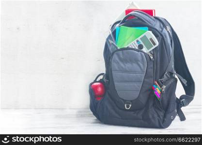 School backpack full of supplies on white desktop. School backpack with supplies