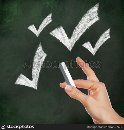 School blackboard and hand with chalk drawing checkmark symbol
