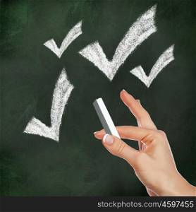 School blackboard and hand with chalk drawing checkmark symbol