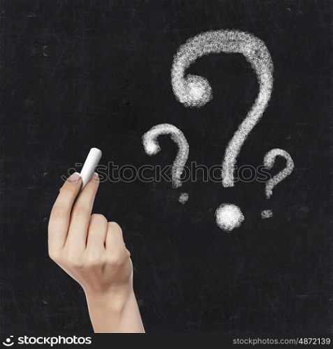 School blackboard and hand with chalk drawing question mark