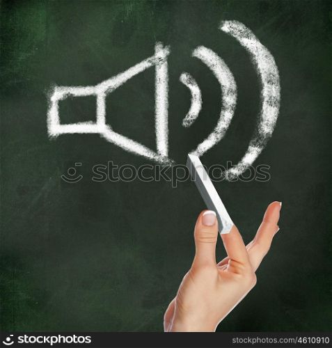 School blackboard and hand with chalk drawing sound symbol