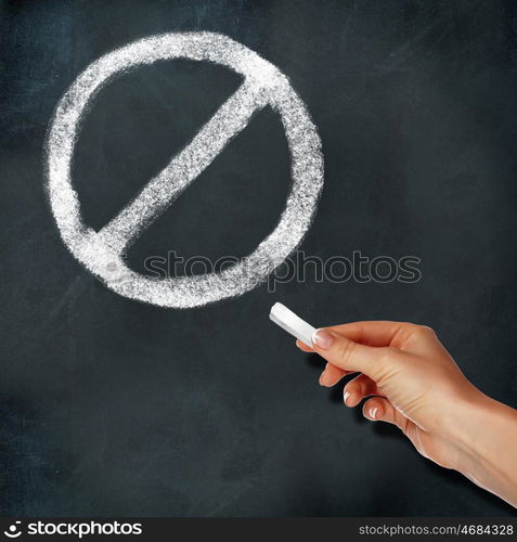 School blackboard and hand with chalk drawing stop symbol