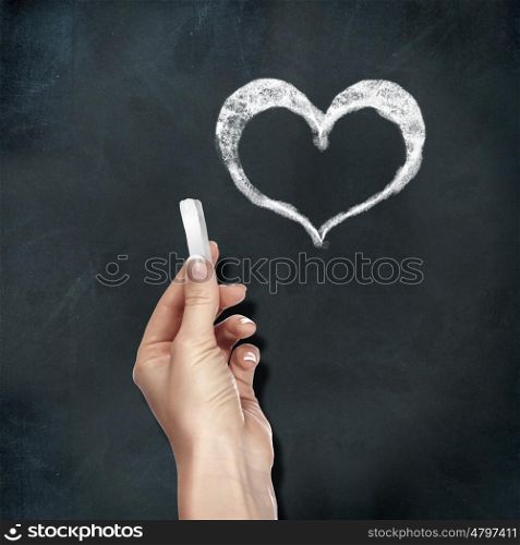School blackboard and human hand with chalk drawing heart symbol
