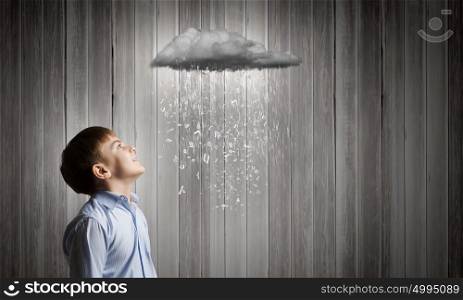 School boy. Cute boy of school age looking at pouring with characters cloud