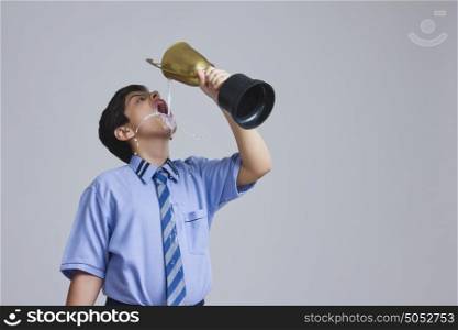 School boy drinking milk from trophy