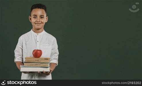 school boy holding books apple