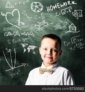 school boy is standing with blackboard behind him