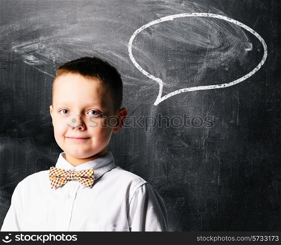 school boy is standing with blackboard behind him