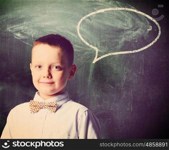 school boy is standing with blackboard behind him. school boy
