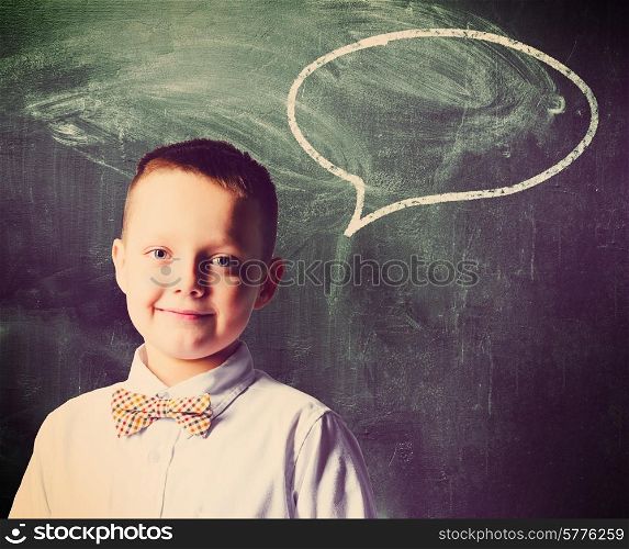 school boy is standing with blackboard behind him. school boy