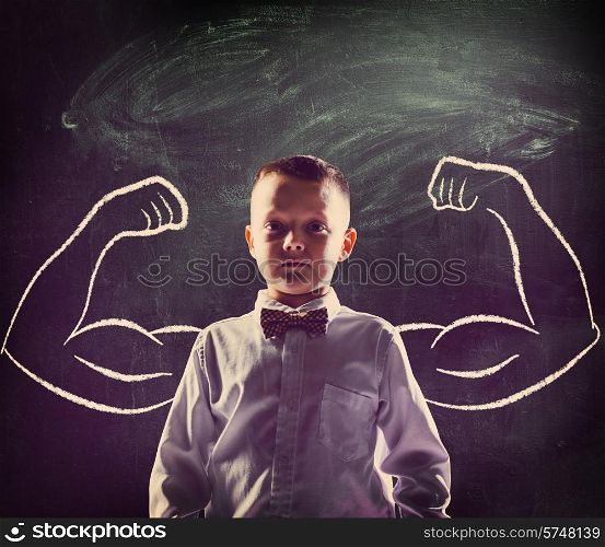 school boy is standing with strong hands on blackboard behind him. school boy
