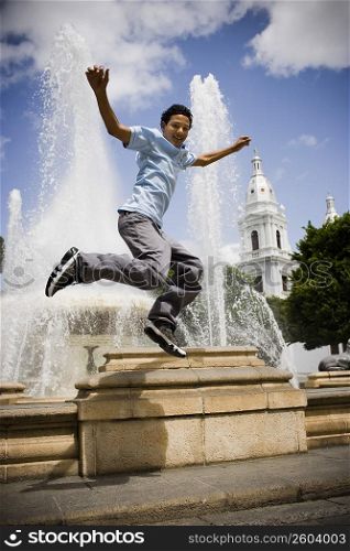 School boy jumping off fountain in center plaza