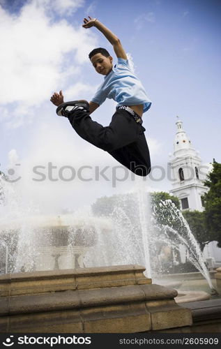 School boy jumping off fountain in center plaza