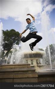 School boy jumping off fountain in center plaza