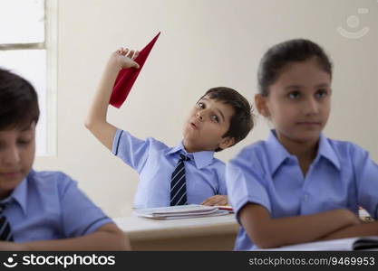 school boy playing with paper plane in class