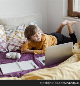 school boy sitting bed with his laptop