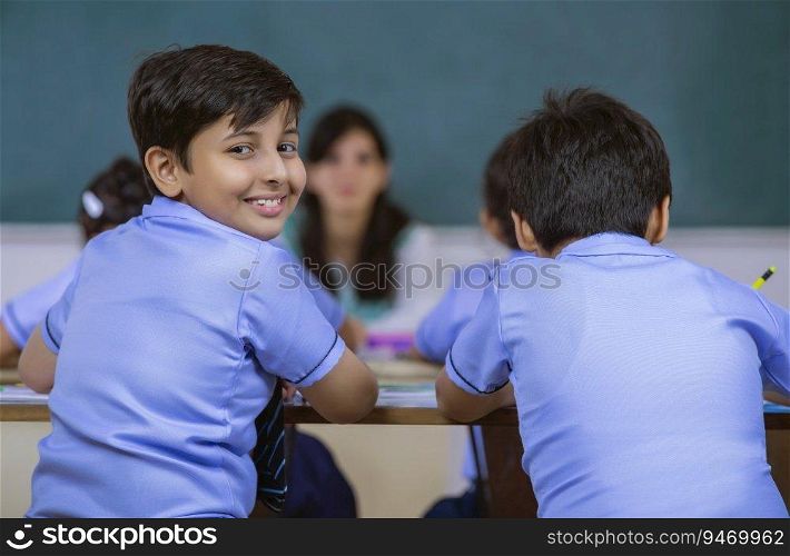 school boy smiling while teacher is sitting in class