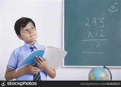 school boy solving maths question on blackboard