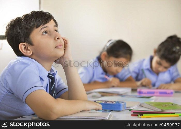 school boy thinking about something in the classroom