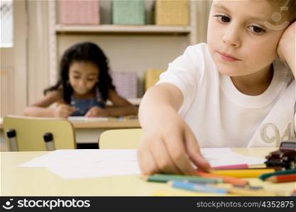 School children drawing on sheets of paper in a classroom