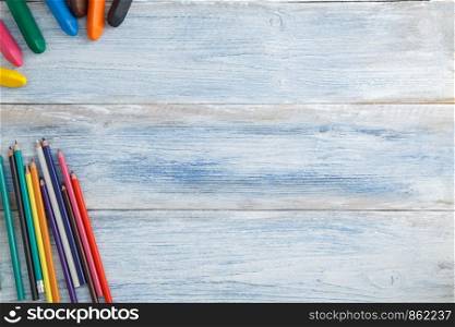 school children's concept. colored pencils and crayons on a blue and white scuffed vintage wooden background. the view from the top. Flat lay
