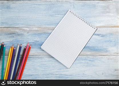 school children&rsquo;s concept. colored pencils or crayons and Notepad on a blue and white scuffed vintage wooden background. the view from the top. Flat lay