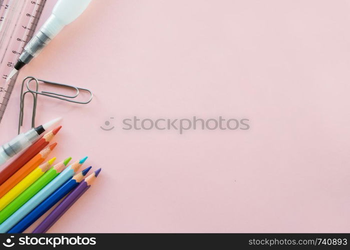 School drawing supplies on pink background. Free space for text. Back to school. Top view border of colour pencils, ruler and brushes. School drawing supplies on pink background. Free space