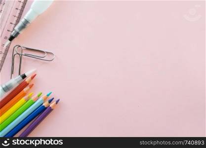 School drawing supplies on pink background. Free space for text. Back to school. Top view border of colour pencils, ruler and brushes. School drawing supplies on pink background. Free space