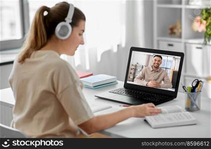 school, education and distance learning concept - happy smiling female student with teacher on laptop computer screen having video call or online class at home. student with laptop having online class at home