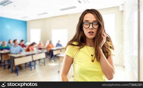 school, education and emotions concept - scared teenage student girl in yellow t-shirt and glasses over classroom background. scared teenage student girl in glasses at school