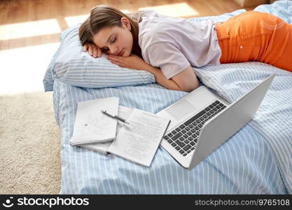 school, education and laziness concept - tired teenage student girl with laptop computer and notebooks sleeping on bed at home. tired student girl with laptop sleeping at home