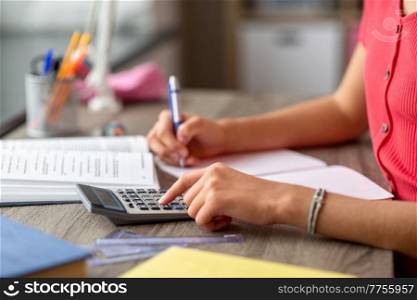 school, education and learning concept - close up of teenage student girl counting on calculator at home. student girl counting on calculator at home